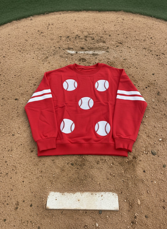 Red sweatshirt with white baseball graphics and stripes on a dark background